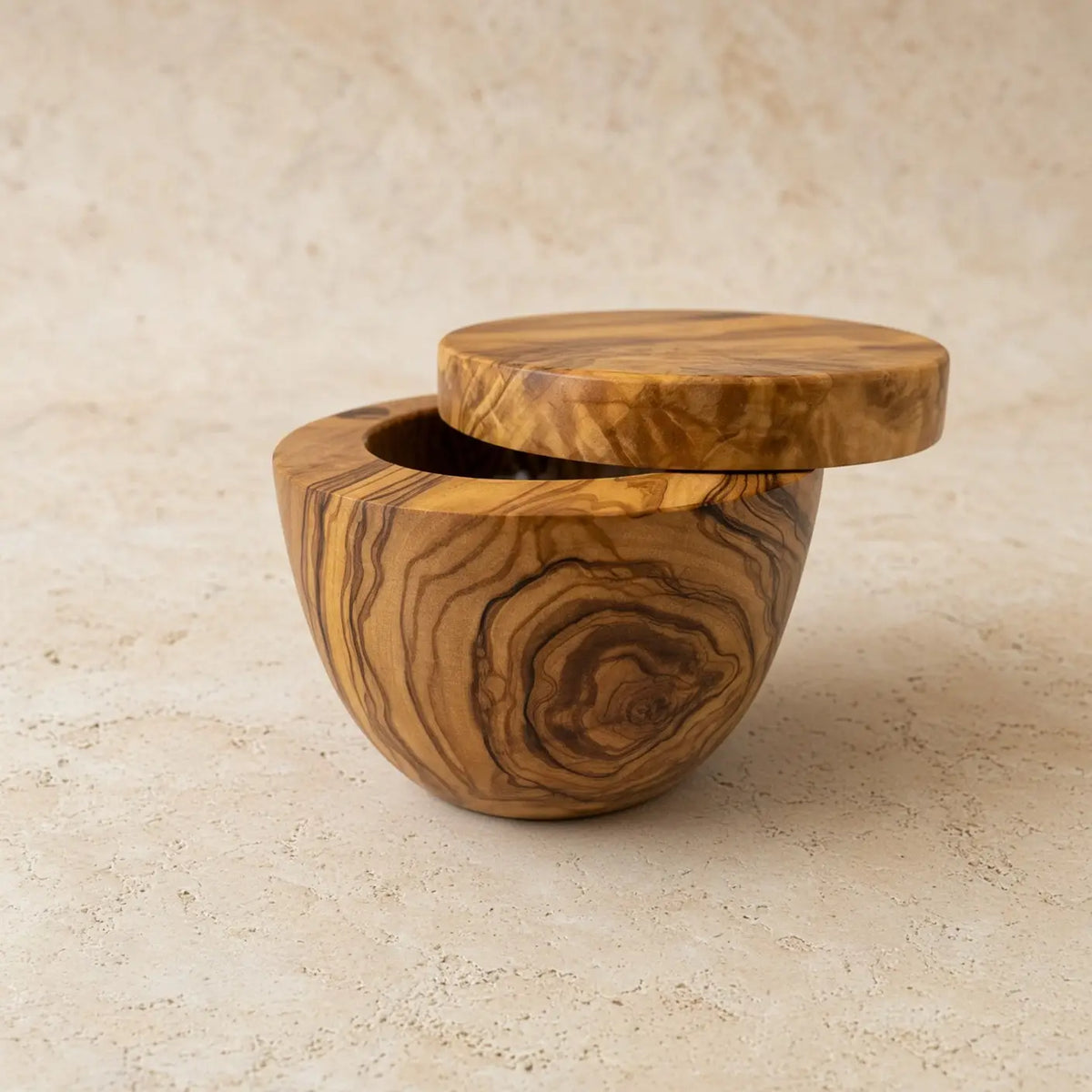 Handmade olive wood salt cellar with swivel lid featuring warm golden and brown swirling grain patterns