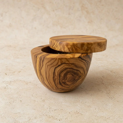 Handmade olive wood salt cellar with swivel lid featuring warm golden and brown swirling grain patterns