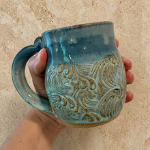 Handmade pottery mug with a blue gradient glaze and earthy brown wave design perfect for everyday use