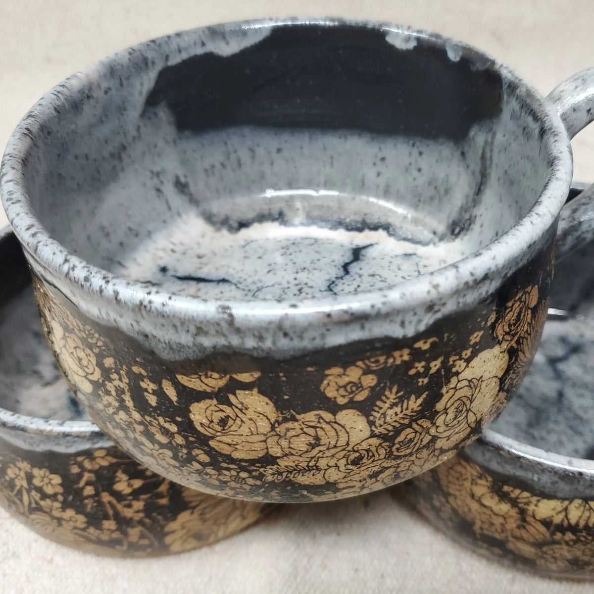 Handmade pottery bowl with floral design and speckled blue and white interior glaze