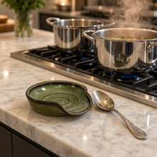 Handmade green ceramic spoon rest with dark brown rim and subtle circular patterns perfect for tea strainer use