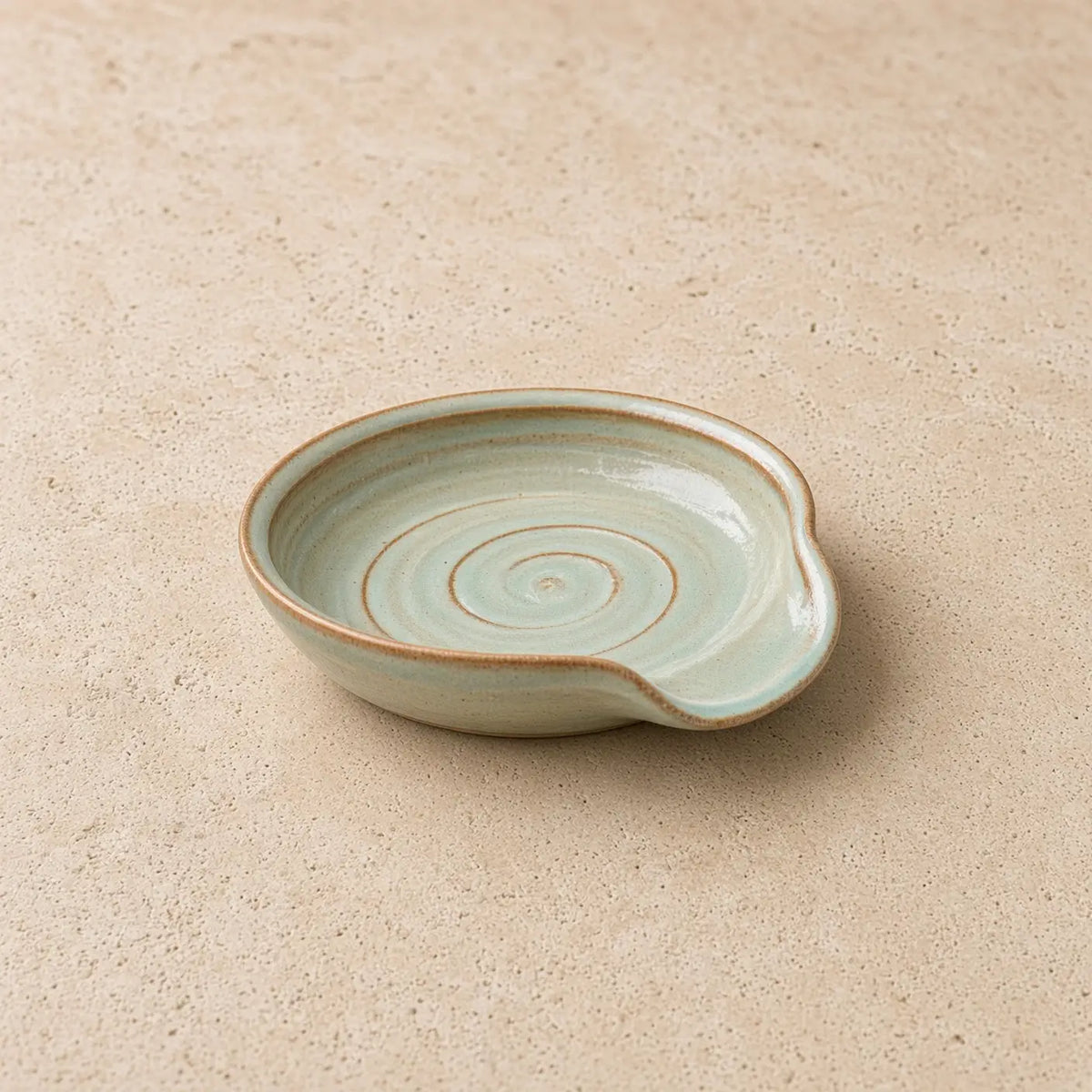 Handmade light green ceramic spoon rest with spiral pattern and rustic finish perfect for tea strainer or spoon rest use