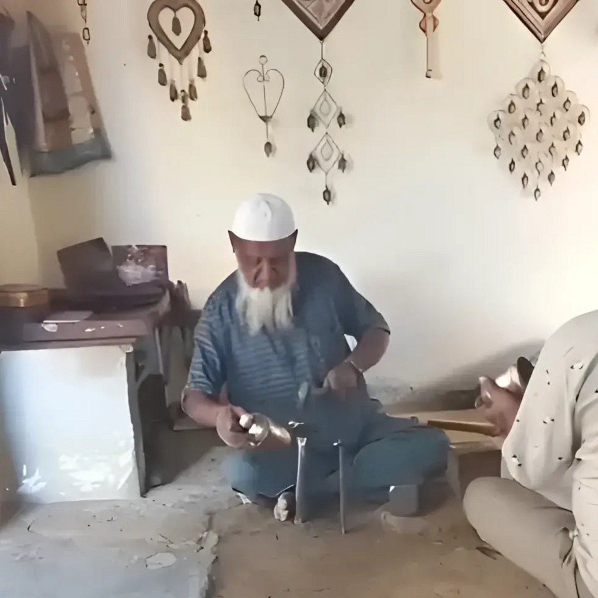 A man with a long white beard kneeling holds handmade rustic cascading harmony bells known for gentle tones