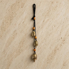 Handmade rustic cascading harmony bells with three brass bells and orange wooden beads on black cord for gentle tones