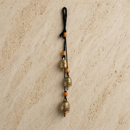 Handmade rustic cascading harmony bells with three brass bells and orange wooden beads on black cord for gentle tones