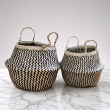 Two handmade belly baskets made of seagrass with black zig-zag patterns and natural fiber handles