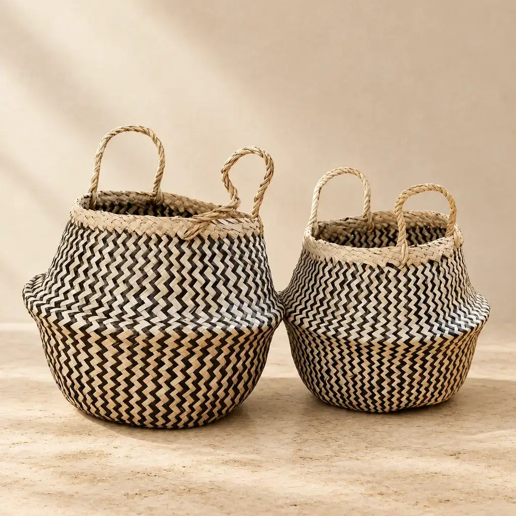 Two handmade seagrass belly baskets with black zig-zag patterns and sturdy handles in natural beige and black