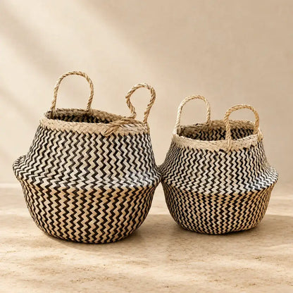 Two handmade seagrass belly baskets with black zig-zag patterns and sturdy handles in natural beige and black