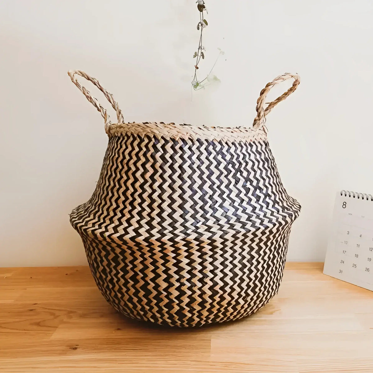 Hand-woven belly basket with black zig-zag pattern and two handles, handmade basket style