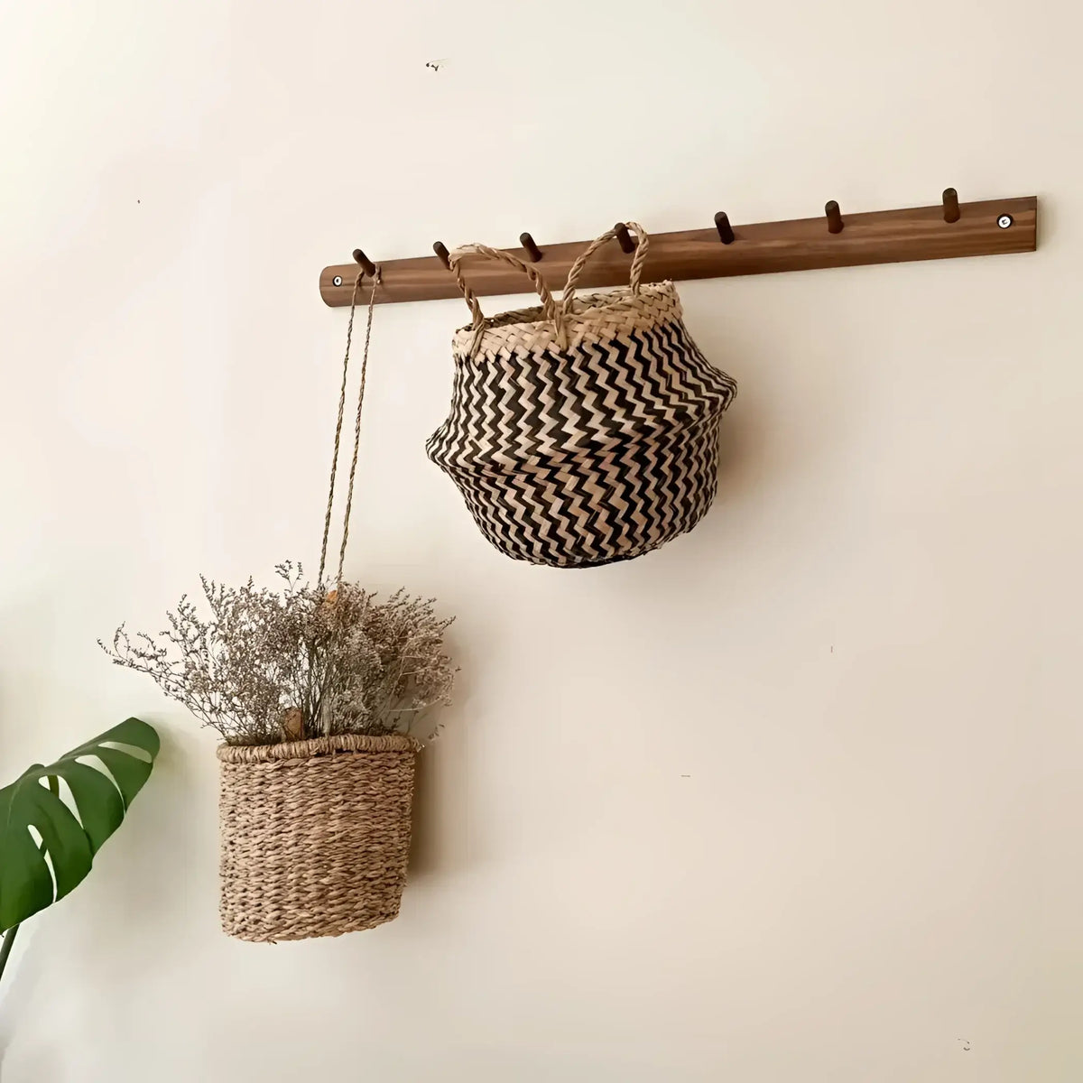 Wall-mounted wooden coat rack with woven belly baskets in black zig-zag patterns