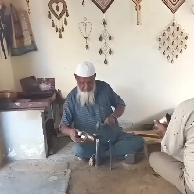 Man with white beard holds large copper zen bell in hands