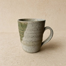 Handmade speckled brown stoneware mug with matte avocado green glaze and subtle horizontal ridges for everyday use