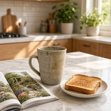 Handmade speckled brown stoneware mug with rustic texture and matte avocado green glaze on marble countertop