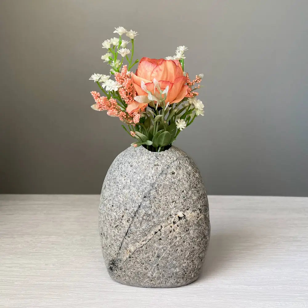 Handmade stone vase with orange flowers and green leaves for eco-friendly decor