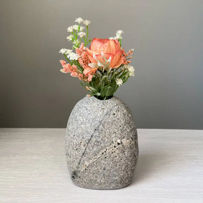 Handmade stone vase with orange flowers and green leaves for eco-friendly decor