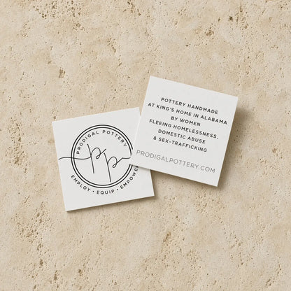 White square business cards with black minimalist typography and circular logo for prodigal pottery handmade white ceramic platter with embossed lace pattern