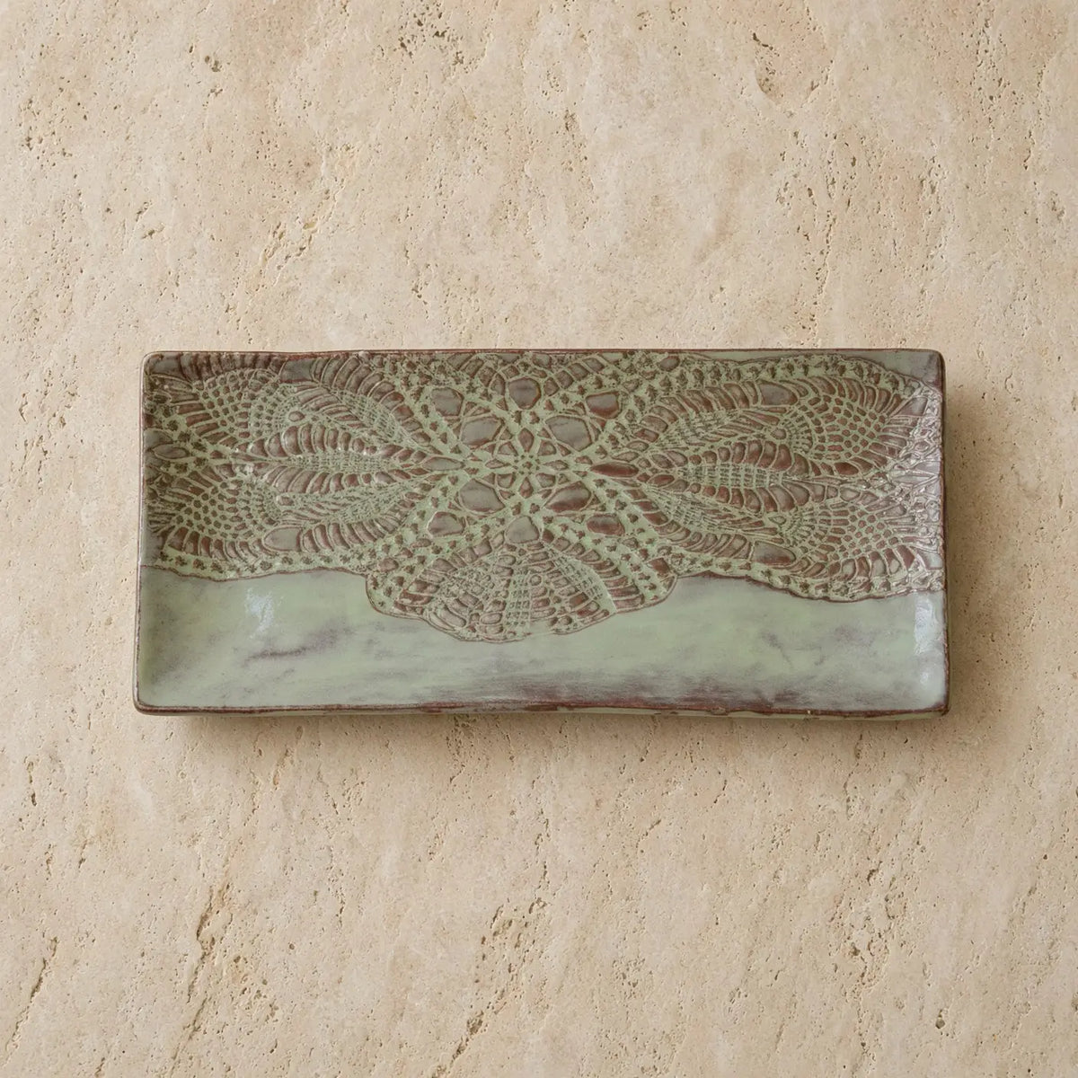 Handmade white ceramic serving platter with embossed lace pattern in earthy tones and soft sage green glaze