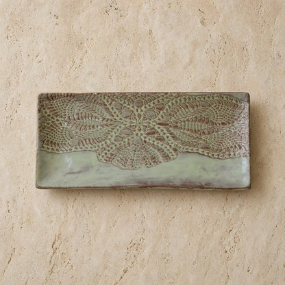 Handmade white ceramic serving platter with embossed lace pattern in earthy tones and soft sage green glaze