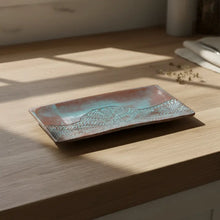 Handmade stoneware serving platter with embossed lace pattern in teal copper tones