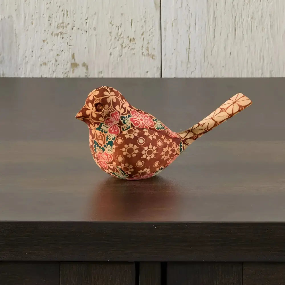 Handmade wooden bird figurine with floral pattern on dark wood surface for decor