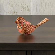 Handmade wooden bird figurine with floral pattern on dark wood surface for decor