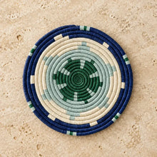 Handwoven african sisal trivet with geometric stars featuring navy blue cream and green concentric rings and spiral center