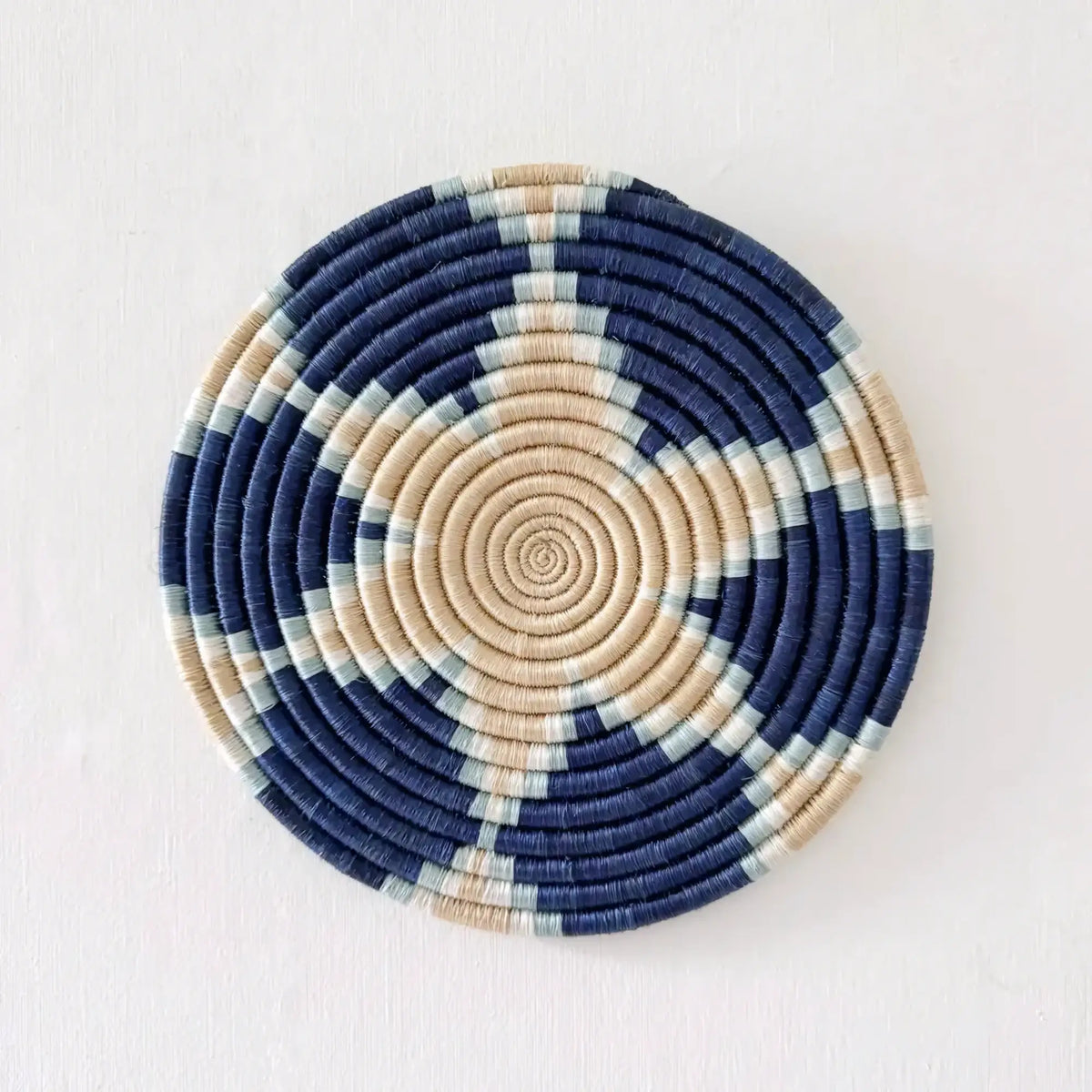 Circular handwoven african sisal trivet with navy beige and mint green concentric spirals for stylish use
