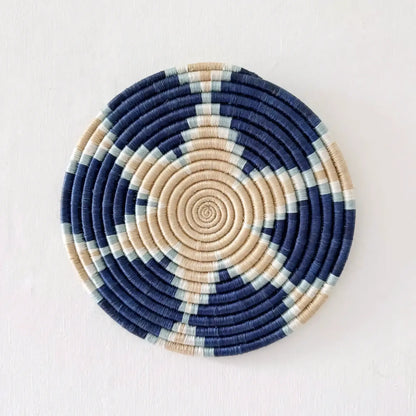 Circular handwoven african sisal trivet with navy beige and mint green concentric spirals for stylish use
