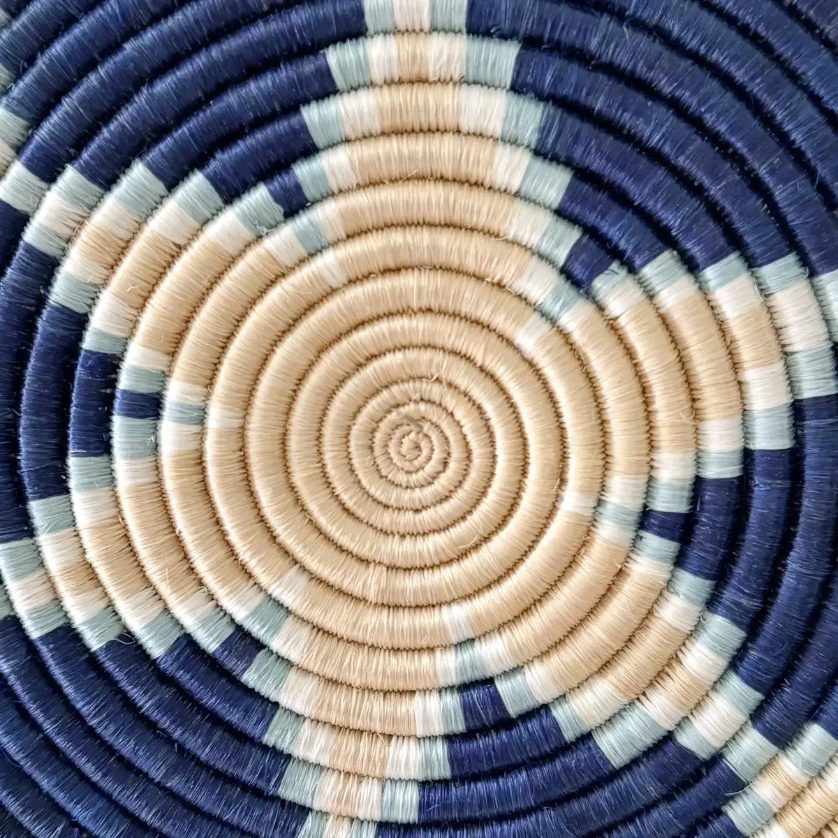 Handwoven african sisal trivet with concentric navy blue beige and light green rings made from sisal fibers
