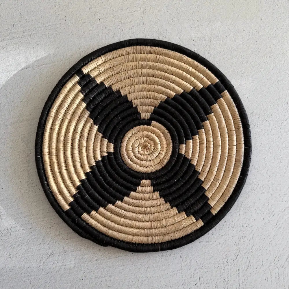 Handwoven african zulu trivet in black and beige woven from ilala palm and wild grasses featuring a spiral pattern from south africa