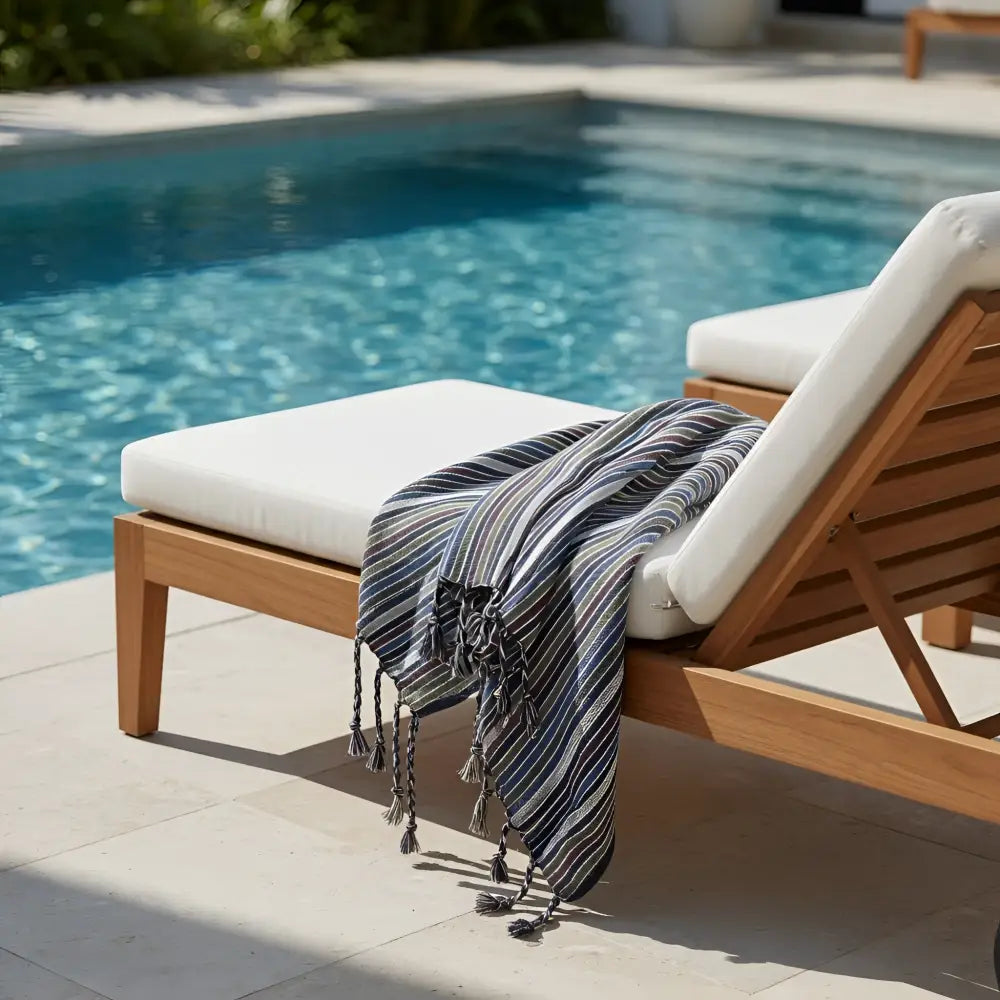 Blue and white striped kekova towel with tassels draped on wooden lounge chair effortlessly combines style