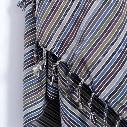 A handwoven earthy striped turkish hand towel with diagonal blue green beige and burgundy stripes and tassels