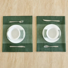 Dark green handwoven ethiopian cotton placemats with subtle stripes paired with white dinnerware and silver flatware fair trade certified