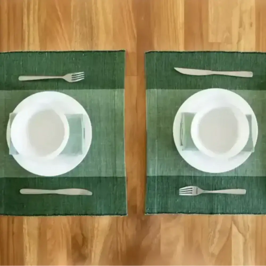 Two place settings with white plates on green handwoven Ethiopian cotton placemats