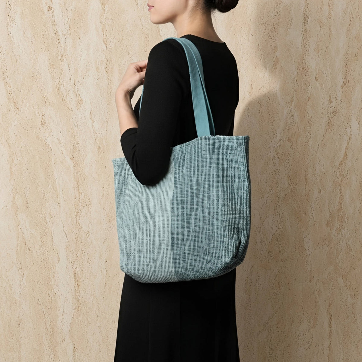 A light blue handwoven ethiopian cotton tote bag with textured grid pattern and button closure shoulder strap
