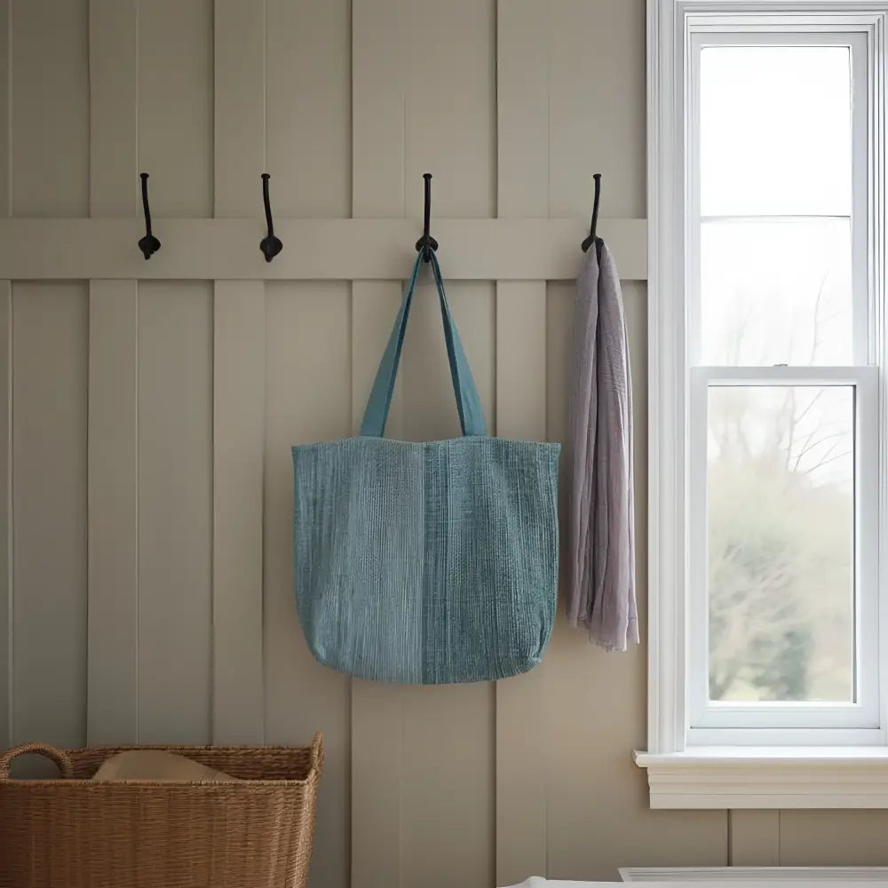 A light blue handwoven ethiopian cotton tote bag with sturdy handles hanging from a wall hook