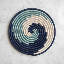 Handwoven sisal trivet with handwoven circular placemat in navy blue teal green and cream colors perfect for kitchen use