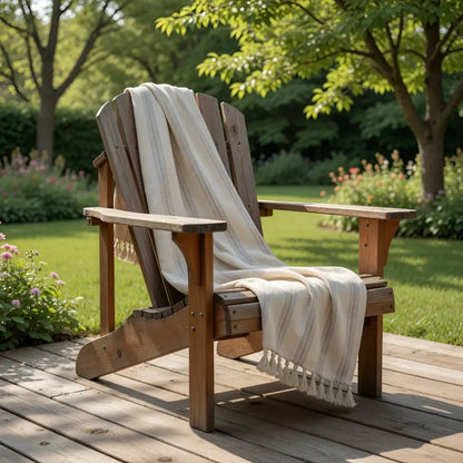 A rustic wooden adirondack chair with a handwoven linen-cotton blend turkish towel featuring light brown stripes draped over it