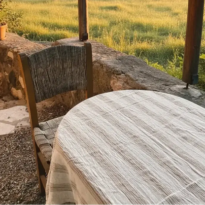 Rustic round wooden table with handwoven light brown striped linen cotton cover