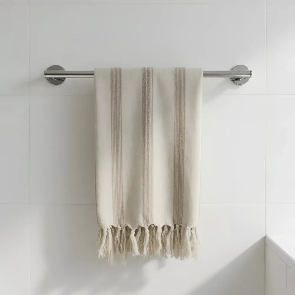 Beige handwoven natural linen cotton blend towel with light brown stripes and soft fringed edges hanging on chrome rod