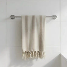 Beige handwoven natural linen cotton blend towel with light brown stripes and soft fringed edges hanging on chrome rod
