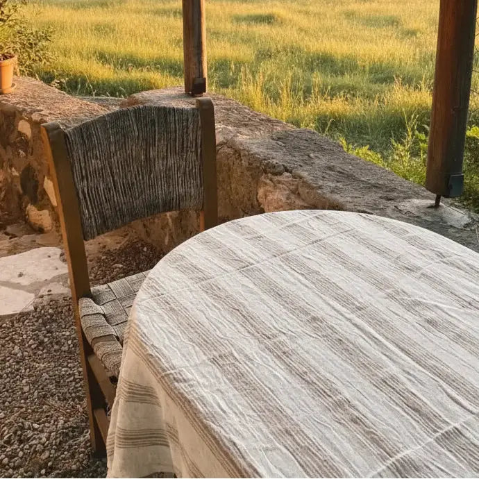 Rustic round wooden table with handwoven light brown striped linen cotton cover