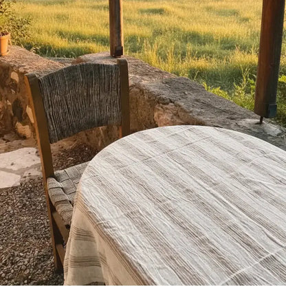 Rustic round wooden table with handwoven light brown striped linen cotton cover