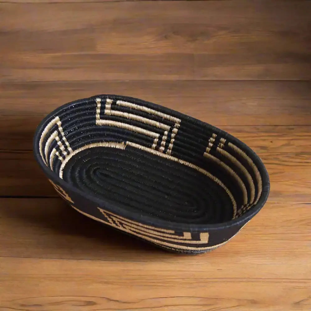 Black and tan oval woven sisal bread basket with geometric patterns by skilled artisans