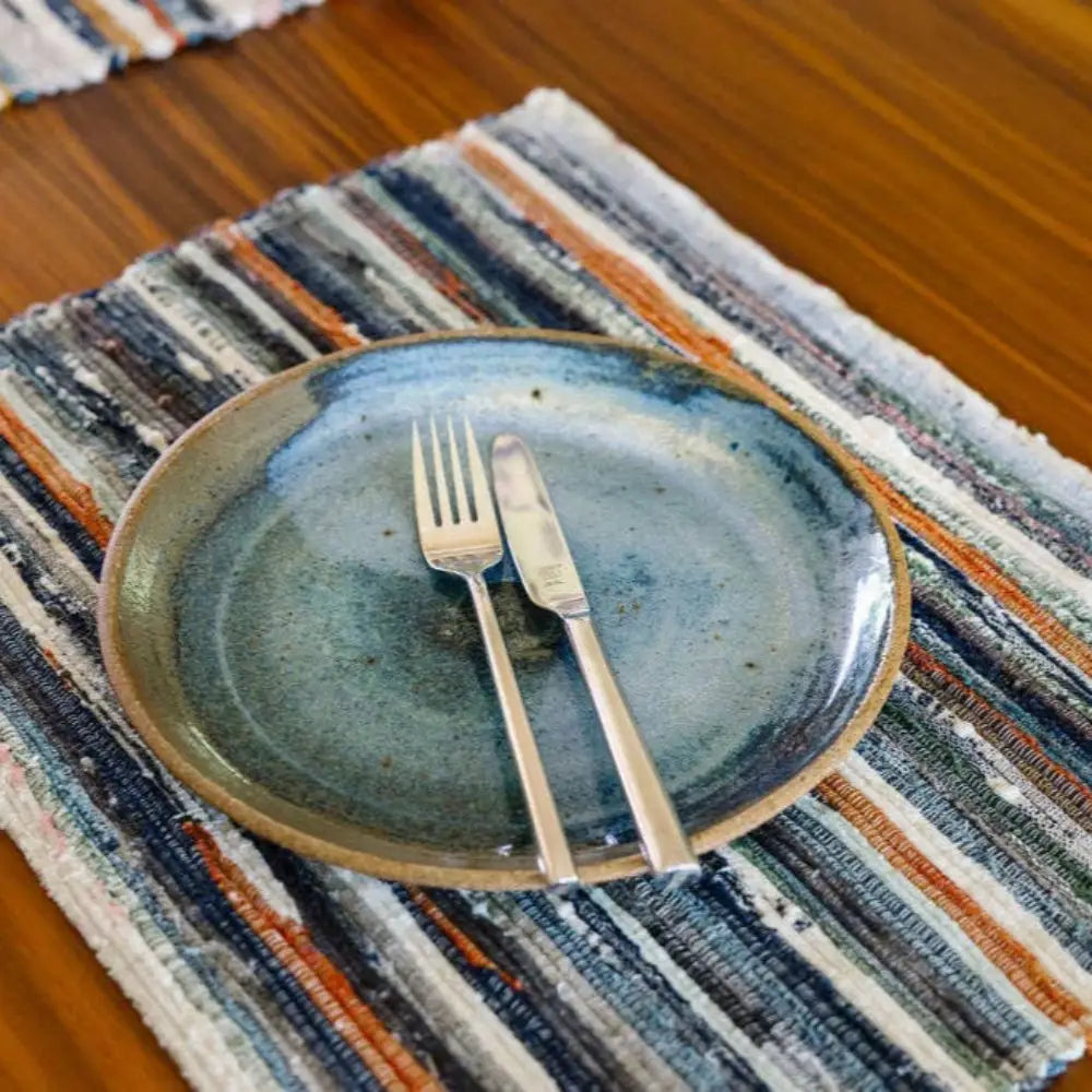 Handwoven Upcycled Fabric Placemat on wood surface with plate and utensils