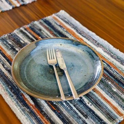 Handwoven Upcycled Fabric Placemat on wood surface with plate and utensils