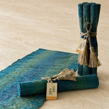 Teal and green striped handwoven vetiver table runner with deep blue accents in a textured natural fiber finish