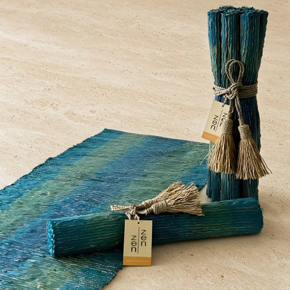 Teal and green striped handwoven vetiver table runner with deep blue accents in a textured natural fiber finish