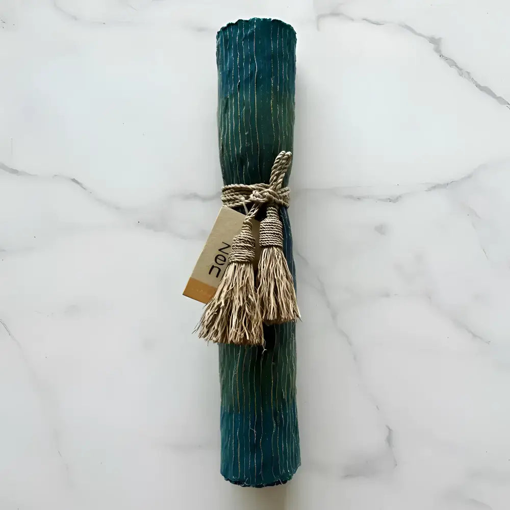 Handwoven vetiver table runner in deep blue teal and green striped fabric roll tied with natural twine and tassels
