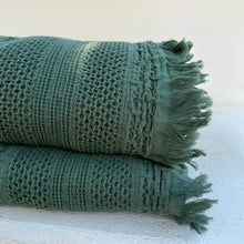 folded green blanket with light background